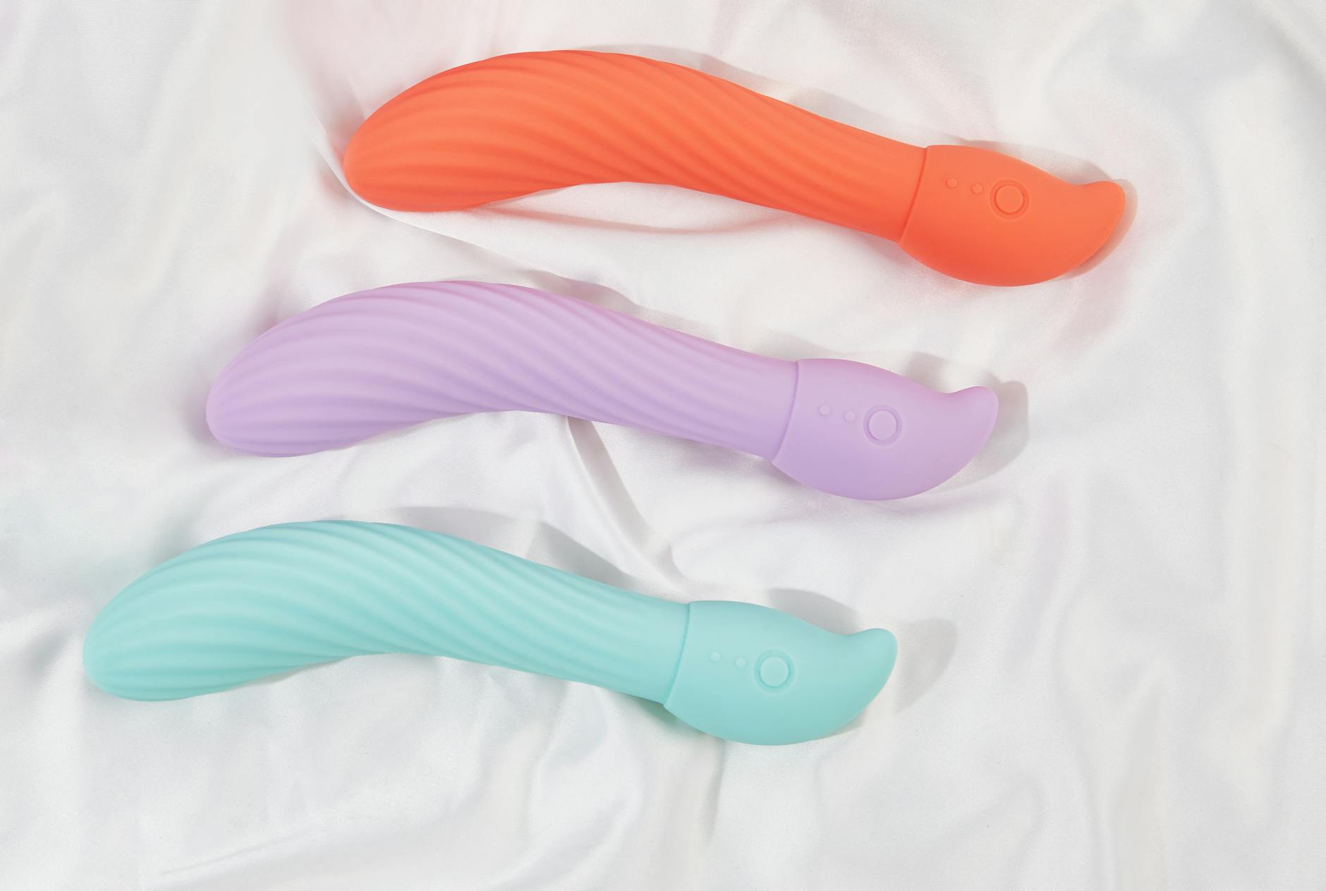 Woman holding blue and pink silicone vibrators, contemplative self-care moment