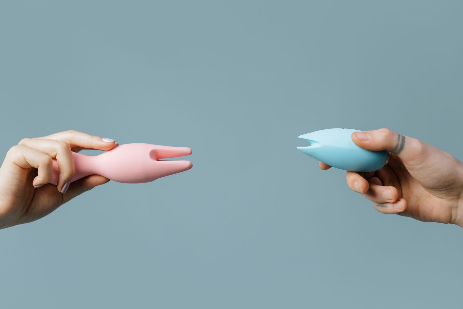Manos sosteniendo un vibrador azul contra un suéter tejido, representando comodidad e intimidad