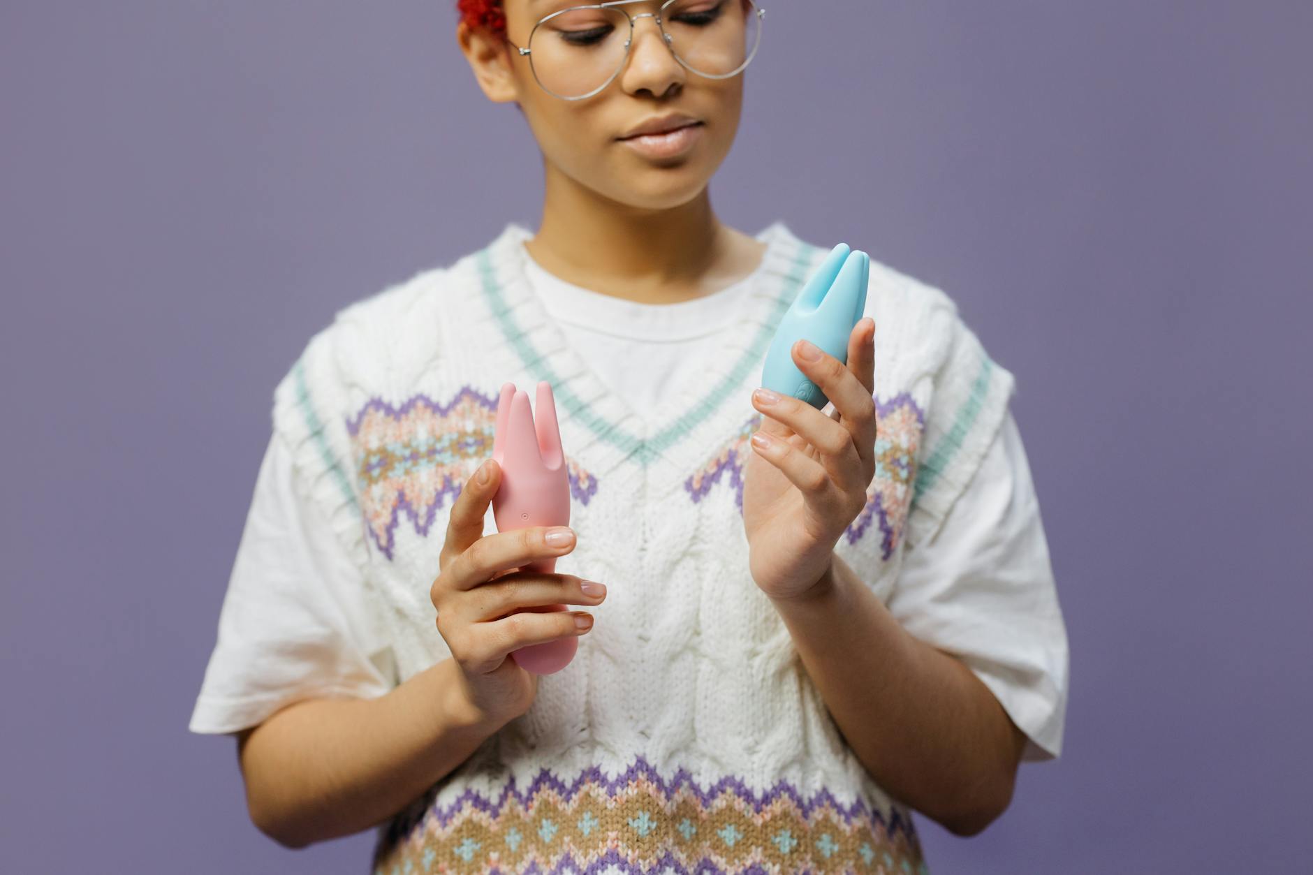 Manos sosteniéndose con un vibrador azul contra un fondo púrpura, representando la intimidad en pareja